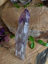Load image into Gallery viewer, Small amethyst wand laying across to wooden stumps with periwinkle and a purple silk flower