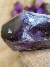 Load image into Gallery viewer, Close up of large amethyst wand point on a wooden stump