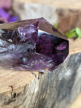 Load image into Gallery viewer, Close up of amethyst wand point on a wooden stump