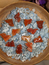 Load image into Gallery viewer, Orange carved agate fish in a bowl of aquamarine chips.
