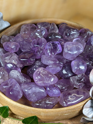 Wooden bowl with tumbled amethyst stones.