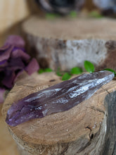 Load image into Gallery viewer, Small amethyst wand laying on a wooden stump

