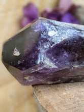 Load image into Gallery viewer, Close up of large amethyst wand point on a wooden stump

