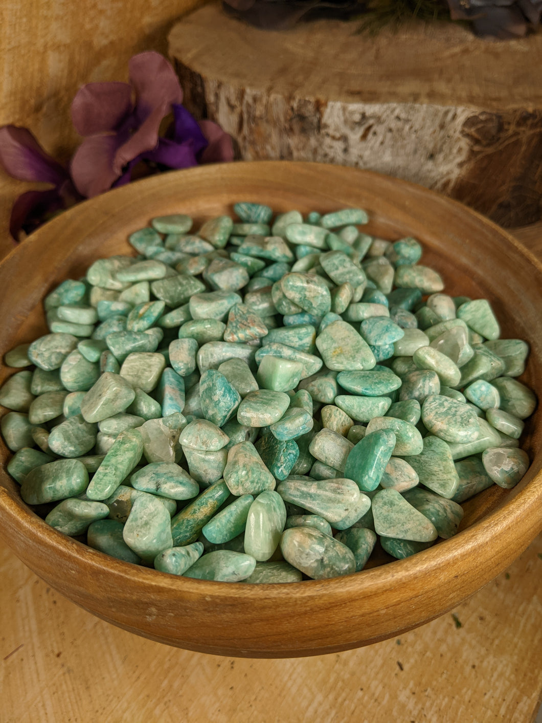 Wooden bowl filled with small greenish blue stones.